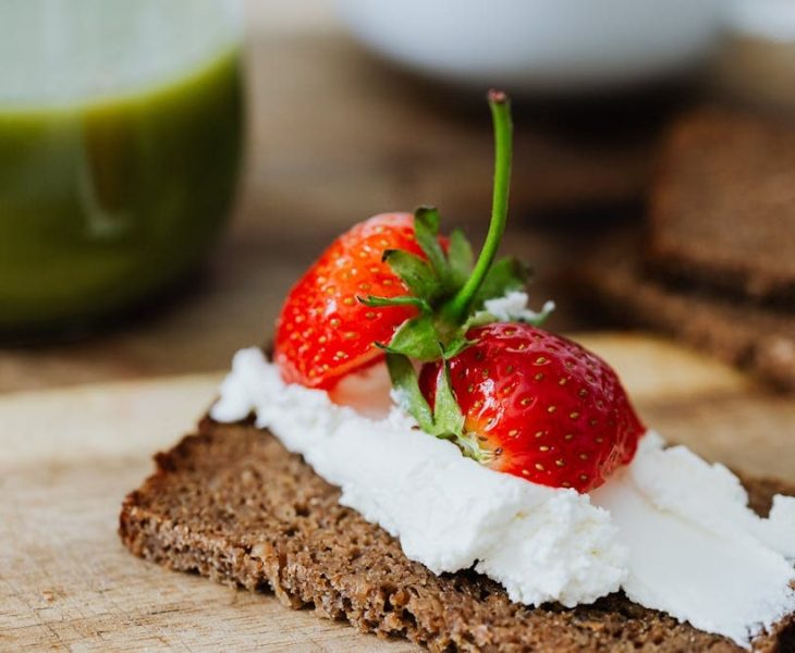 Rye bread topped with cream and juicy strawberries, perfect for a sweet treat.