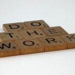 Motivational message spelled out with scrabble tiles on white background.