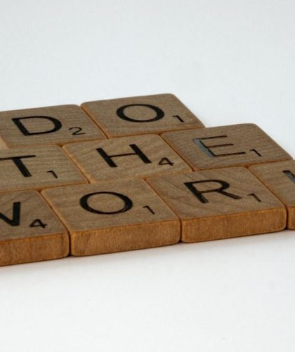 Motivational message spelled out with scrabble tiles on white background.