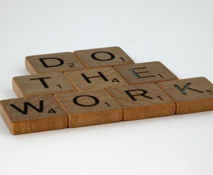 Motivational message spelled out with scrabble tiles on white background.