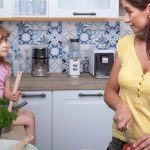 A mother and daughter enjoy cooking together in a cozy modern kitchen, fostering family bonds.