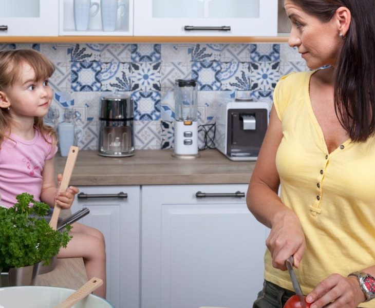 A mother and daughter enjoy cooking together in a cozy modern kitchen, fostering family bonds.